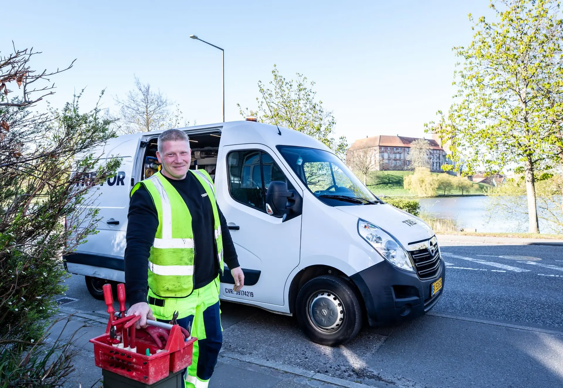 Tradesman with a toolbox standing beside a white work van